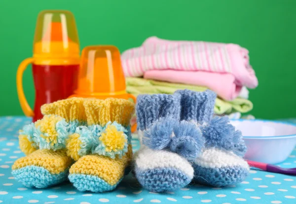 Composition avec chaussons au crochet pour bébé, vêtements et autres choses sur fond de couleur — Photo