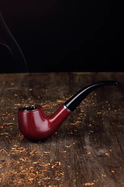 Smoking pipe and tobacco on wooden table on black background — Stock Photo, Image