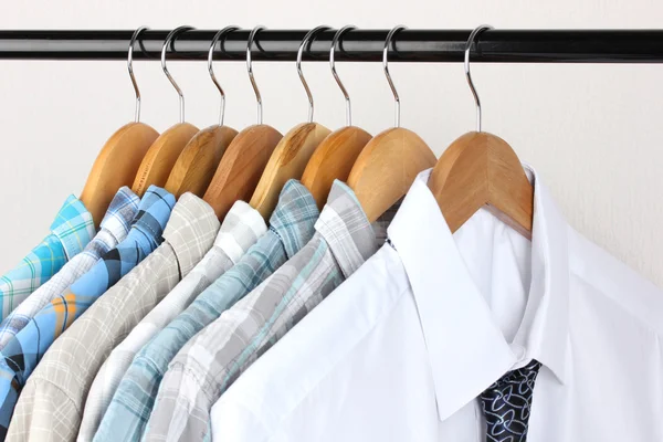 Shirts with ties on wooden hangers on light background — Stock Photo, Image