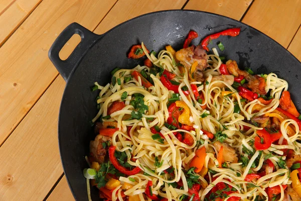 Noodles with vegetables on wok on wooden background — Stock Photo, Image