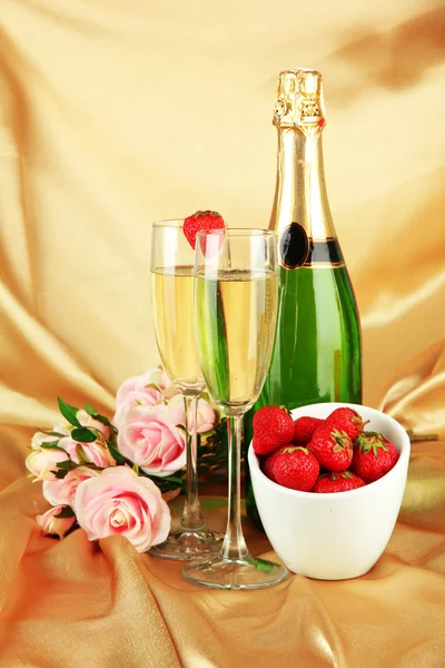 Romantic still life with champagne, strawberry and pink roses, on color fabric background — Stock fotografie