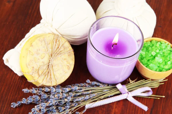 Bodegón con vela de lavanda, jabón, bolas de masaje, botellas, jabón y lavanda fresca, sobre mesa de madera sobre fondo de madera — Foto de Stock