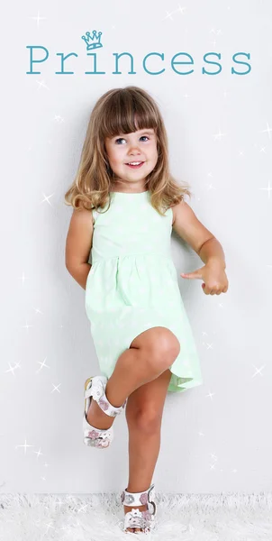 Aranyos kislány a szőnyegen, szürke háttér — Stock Fotó