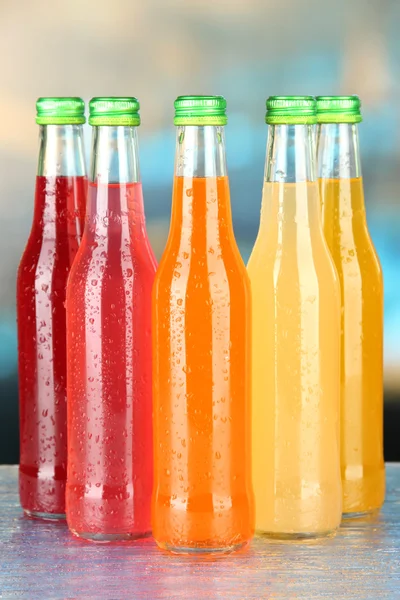 Bottles with tasty drinks on bright background — Stock Photo, Image