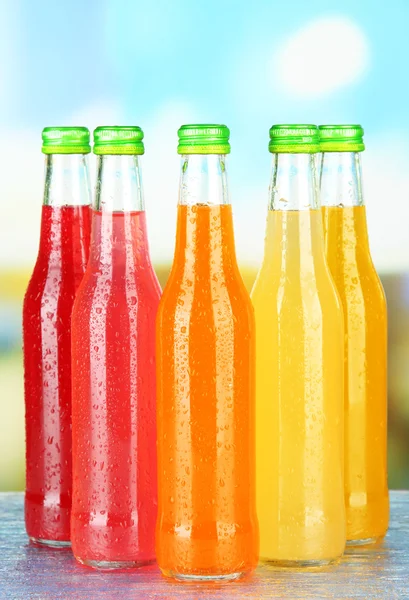 Botellas con bebidas sabrosas sobre fondo brillante — Foto de Stock