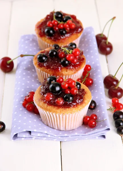 Muffins saborosos com bagas na mesa de madeira branca — Fotografia de Stock