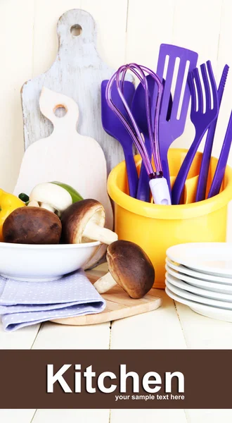 Plastic kitchen utensils in cup on wooden table — Stock Photo, Image