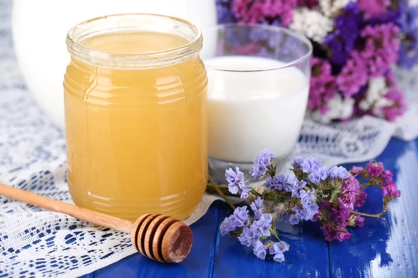 Honig und Milch auf blauem Holztisch in Großaufnahme — Stockfoto