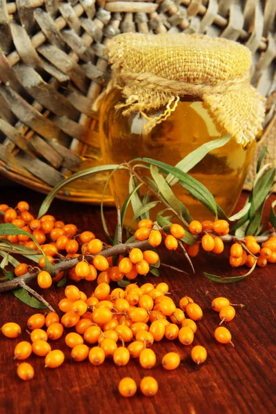 Branch of sea buckthorn with honey on table on wicker background — Stock Photo, Image
