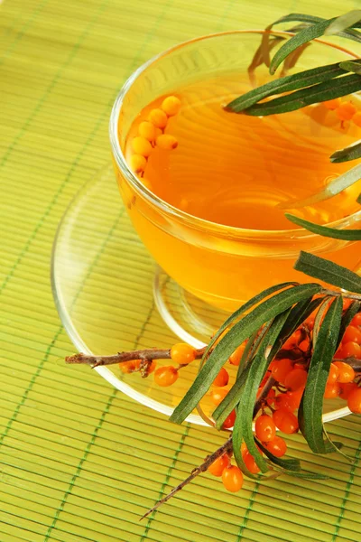 Branches of sea buckthorn with tea on bamboo background — Stock Photo, Image