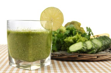 Bardak yeşil sebze suyu ve beyaz arka plan üzerinde masa örtüsü sebze