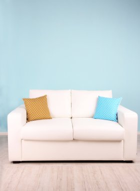 Odada mavi zemin üzerine beyaz kanepe