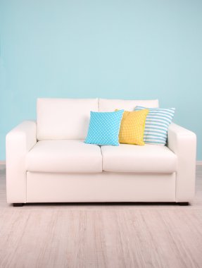 Odada mavi zemin üzerine beyaz kanepe