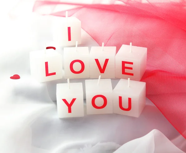 Candles with printed sign I LOVE YOU, on white fabric background — Stock Photo, Image