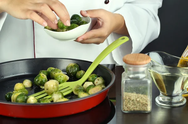 Chef prépare frresh choux de Bruxelles dans une casserole sur la surface de cuisson close-up — Photo