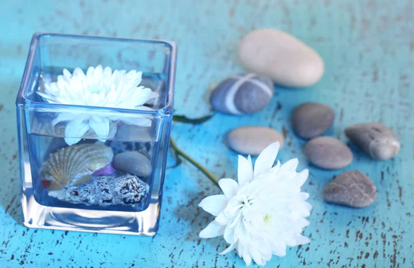 Jarrón decorativo con flores, agua y piedras sobre mesa de madera —  Fotos de Stock