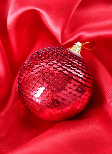 Bola de Natal bonita em pano de cetim vermelho — Fotografia de Stock