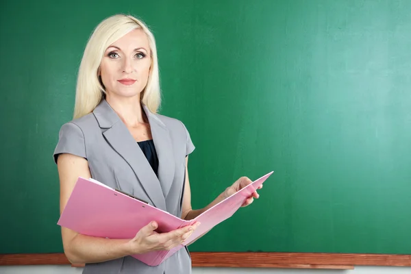 Lehrerin mit Mappe in der Nähe der Tafel in Großaufnahme — Stockfoto