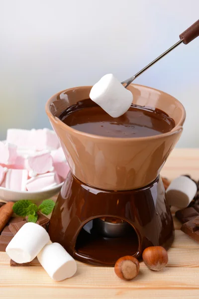 Шоколадний фонтан з зефірними цукерками, на дерев'яному столі, на світлому фоні — стокове фото