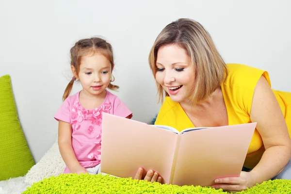 Liten flicka med mamma läsa bok i sängen — Stockfoto