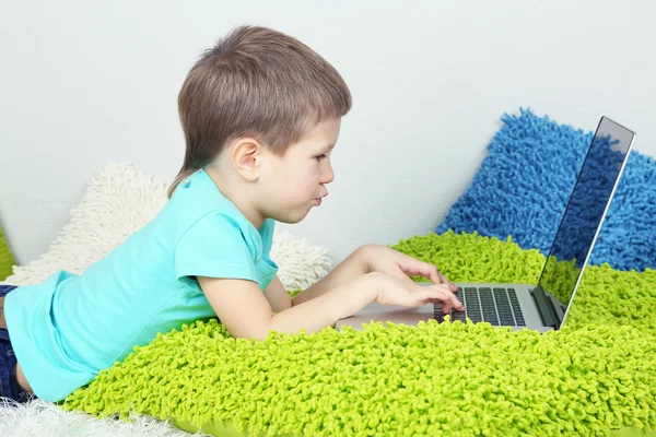 Liten pojke med laptop på sängen — Stockfoto
