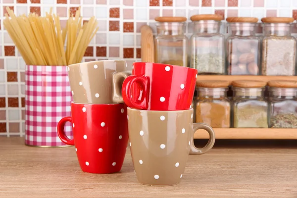 Cups in kitchen on table on mosaic tiles background — Stock Photo, Image