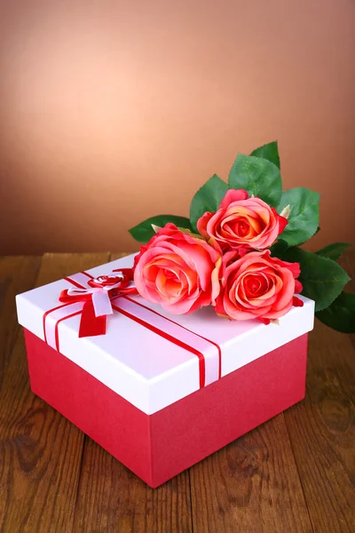 Hermosa caja de regalo con flores en la mesa sobre fondo marrón — Foto de Stock