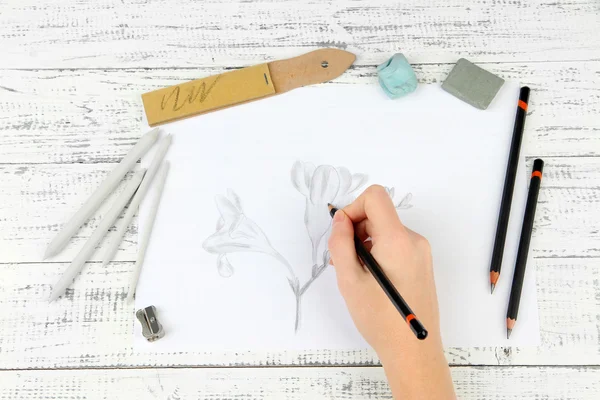 Dessine à la main un croquis avec des matériaux d'art professionnels, sur une table en bois — Photo