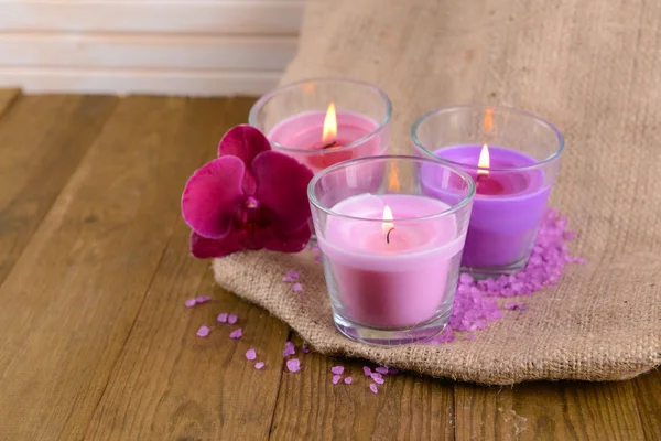 Kompozycja z piękne kolorowe świece, sól morska i kwiaty orchidei, na tle drewniane — Zdjęcie stockowe