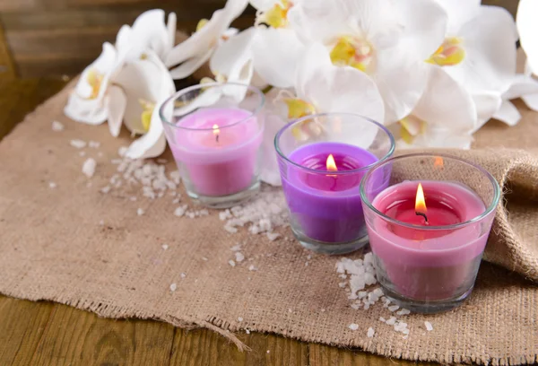 Composição com belas velas coloridas, sal marinho e flores de orquídeas, em fundo de madeira — Fotografia de Stock
