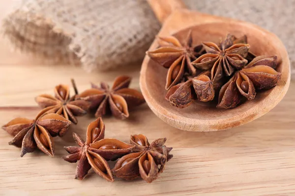 Star anise in wooden spoon, on wooden background — Stock Photo, Image