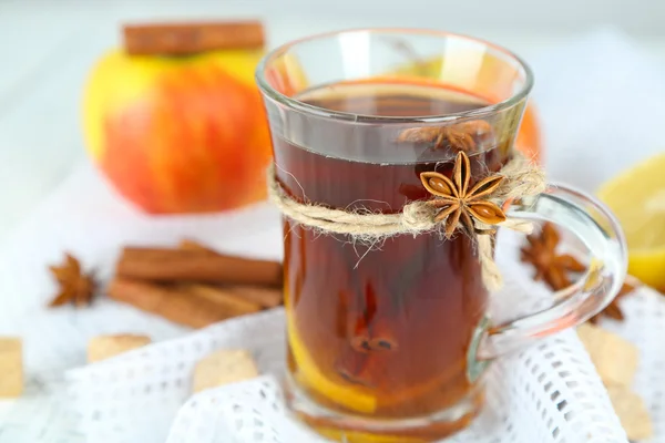 Horký nápoj ve sklenici s ovocem a kořením, na dřevěné pozadí — Stock fotografie