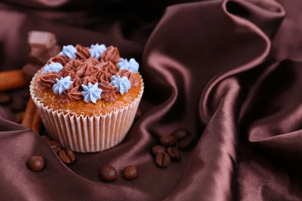 Välsmakande cupcake med smörkräm, på färg tyg bakgrund — Stockfoto