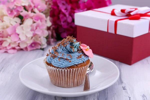Välsmakande cupcake med smörkräm, på plattan, färg trä bakgrund — Stockfoto