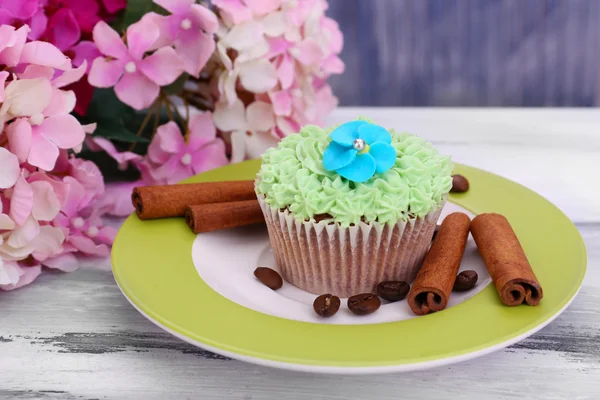 Välsmakande cupcake med smörkräm, på plattan, färg trä bakgrund — Stockfoto