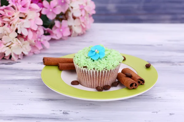 Finom cupcake vaj tejszín, lemez, színes fából készült háttér — Stock Fotó