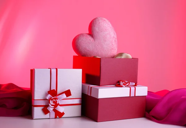 Pila di scatole regalo e cuore decorativo, su sfondo a colori — Foto Stock