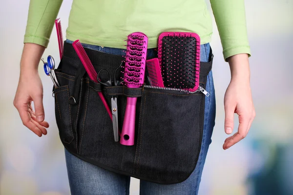 Woman hairdresser with tool belt on bright background — Stock Photo, Image