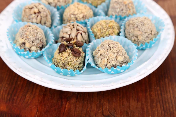 Set van chocolade snoepjes, op plaat, op houten achtergrond — Stockfoto