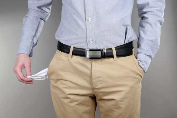 Man showing his empty pocket on grey background — Stock Photo, Image