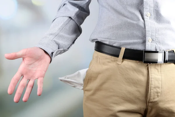 Homem mostrando seu bolso vazio no fundo brilhante — Fotografia de Stock