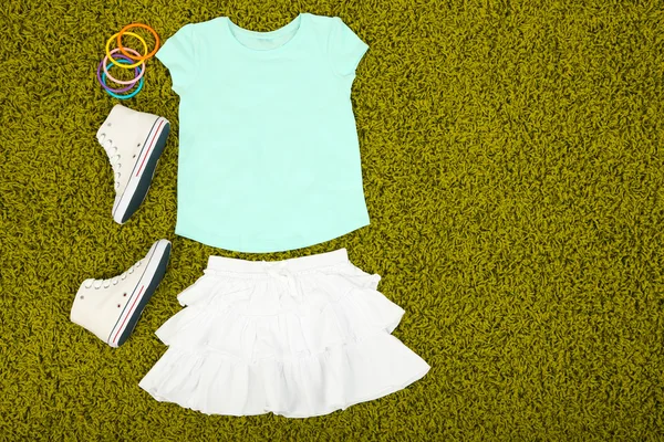 Piękne ubrania dla dziewczynki na zielony dywan — Zdjęcie stockowe