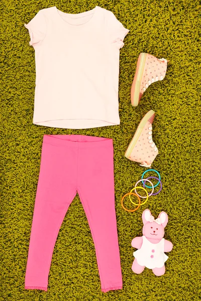 Beautiful clothes for little girl on green carpet — Stock Photo, Image