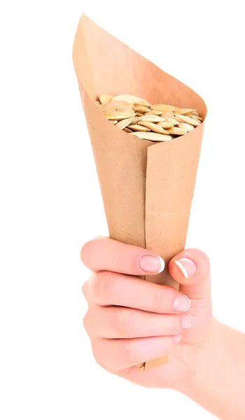 Hand som håller papper kornett med pumpafrön isolerad på vit — Stockfoto