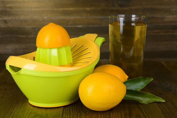 Citrus press and lemons on table on wooden background — Stock Photo, Image