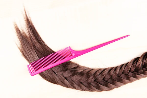 Long hair with brush on pink background — Stock Photo, Image