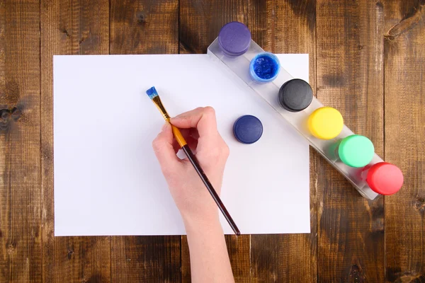 Hand-Pinsel mit Farben und Papier auf Holzgrund — Stockfoto
