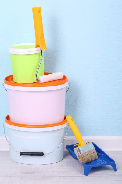 Pinturas, rollo y pincel en el suelo en la habitación sobre fondo de pared — Foto de Stock