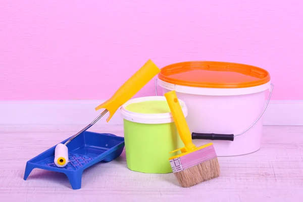 Farby, rolki i pędzel na podłodze w pokoju na tle ściany — Zdjęcie stockowe