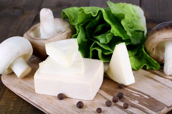 Сливочный сыр с овощами и зеленью на деревянной доске крупным планом — стоковое фото
